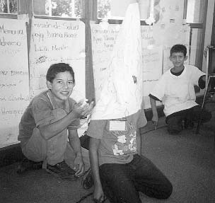 Los niños exploraron cómo ayudarse unos a otros en diferentes desastres. Aquí, en un juego de roles, un niño actúa como parte de un volcán, que tiembla y retumba y luego se rompe. (La erupción ocurre cuando el niño en cuclillas detrás del volcán arroja al aire puñados de bolitas de papel).