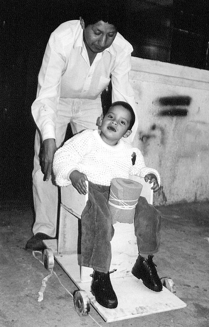 El padre de un niño con parálisis cerebral ayudó a los participantes en un Curso de Capacitación de Rehabilitación Basada en la Comunidad en Ecuador a construir este asiento especial con ruedas de madera. Un ensayo fotográfico sobre el curso comienza en la pág. )