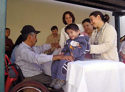 Raymundo, quien está a cargo del Taller de Sillas de Ruedas para niños, evalúa a un niño para una silla de ruedas hecha a medida.