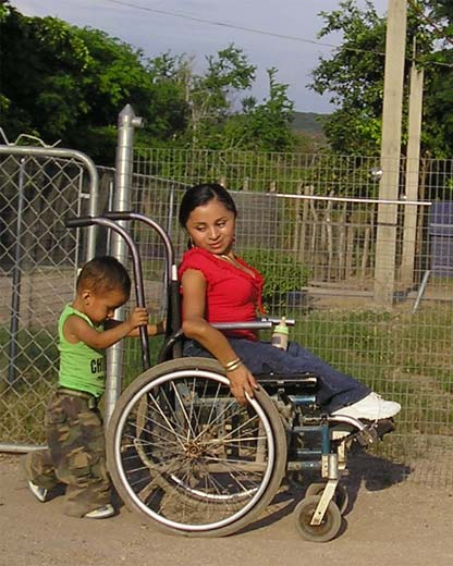 Virginia, una mujer joven con enfermedad de fragilidad ósea, ha recibido ayuda de PROJIMO y HealthWrights desde que tenía 5 años. Ella ahora trabaja en PROJIMO. Su saludable hijo de 1 año y medio, José Carlos, ya está orgulloso de ayudar a empujar la silla de ruedas de su madre.