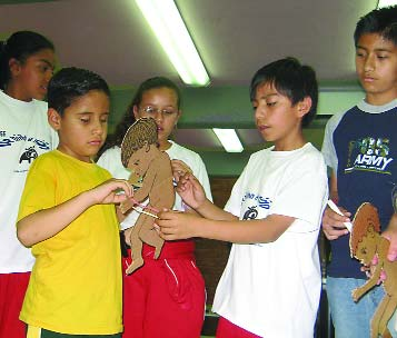 Los niños ayudaron al niño ciego, Melchor, a medir el grosor del brazo de un niño de cartón. Como no puede ver, en lugar de una tira de medición de color, usa una cuerda con nudos para marcar cuándo un niño está bien, en riesgo o demasiado delgado. Al sentir los nudos, Melchor pudo determinar qué niños estaban desnutridos.