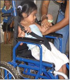 La silla de ruedas de María era demasiado grande para ella. Las correas, que pasan sobre sus hombros y pasan entre sus piernas, no evitan que su cuerpo se arquee y se deslice hacia adelante.
