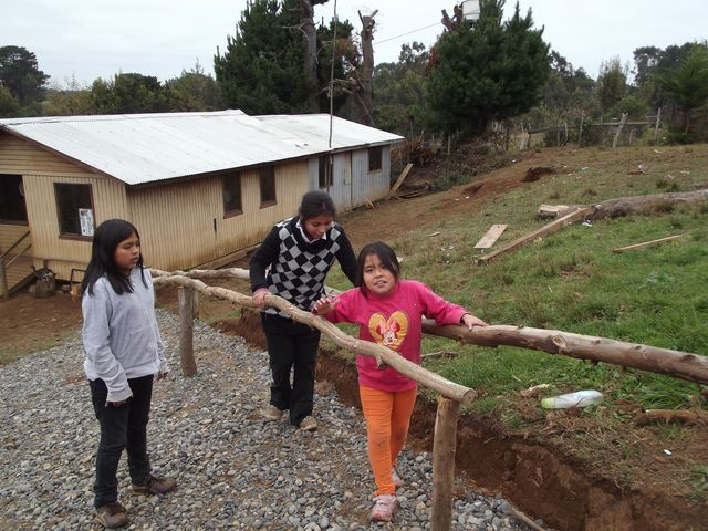 Dos niñas con parálisis cerebral atáxica usan barras paralelas rústicas para subir la pendiente empinada que lleva desde su casa hasta la carretera. El padre encontró la idea en "El Niño Campesino Deshabilitado".