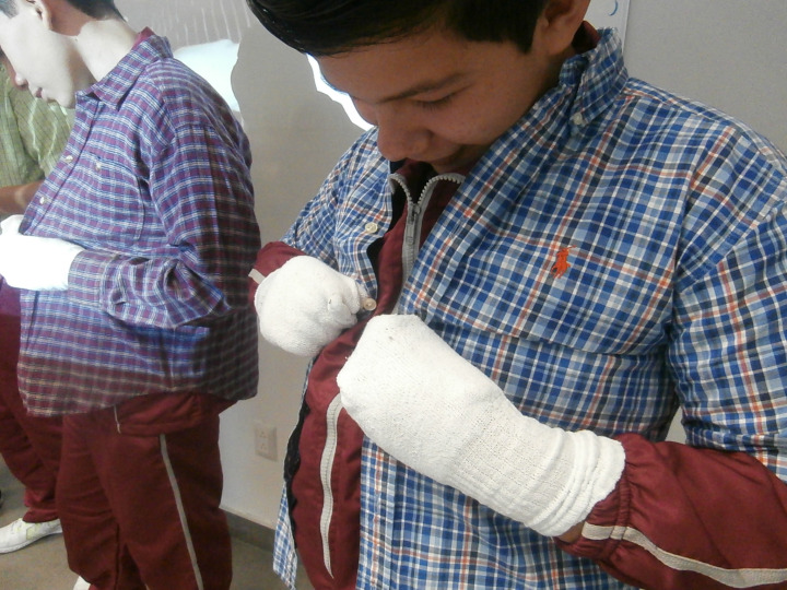 Este niño luchó para abotonarse la camisa con calcetines en las manos.