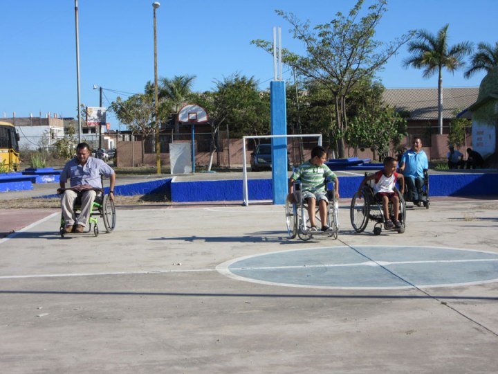 Aquí dos niños sostienen una carrera de silla de ruedas en la cancha de básquetbol.