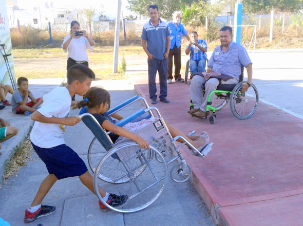 Aquí los niños aprenden cómo ayudar a una persona en silla de ruedas a subir una rampa muy inclinada.