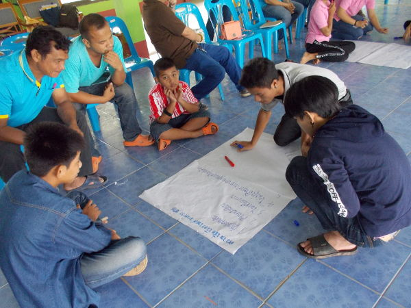 Al final del juego de roles, los participantes discuten sobre lo que aprendieron y escriben sus conclusiones en carteles. Los cuatro jóvenes sentados alrededor del póster son todos "amigos" en el proyecto de prestadores de cuidados en el hogar.