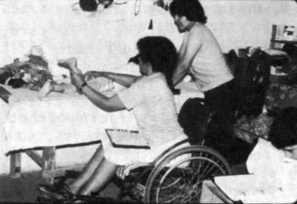 Mari (before the flare-up of her bone infection) examines a disabled child while Julio, a quadriplegic team member, while refering to the ‘Disabled Village Children's Manual’ which is nearing completion.