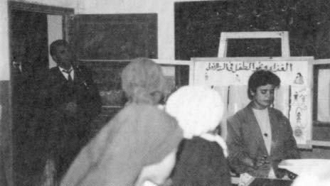 Security police stand in the doorway of a village school where an adult literacy course organized with the help of medical students is taking place.