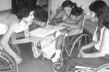 Because Julio was the person with the least power physically at PROJIMO, he was given a job that gave him more power socially: recording the hours worked and wages earned by each worker. Here he writes with a plastic pen holder strapped to his hand.