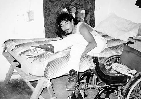Julio uses the spastic straightening of his knees to transfer from wheelchair to bed.