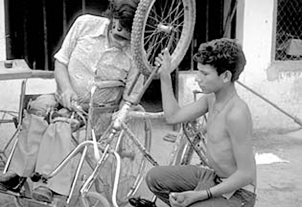 Leopoldo Leyva, a wheelchair rider and builder at PROJIMO, welds a village boy's broken bicycle.