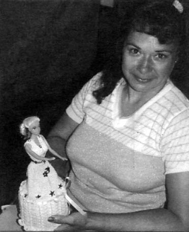 Cecilia shows a doll whose lovely dress—which she knitted—holds a roll of toilet paper. She sells these as artful bathroom accessaries.