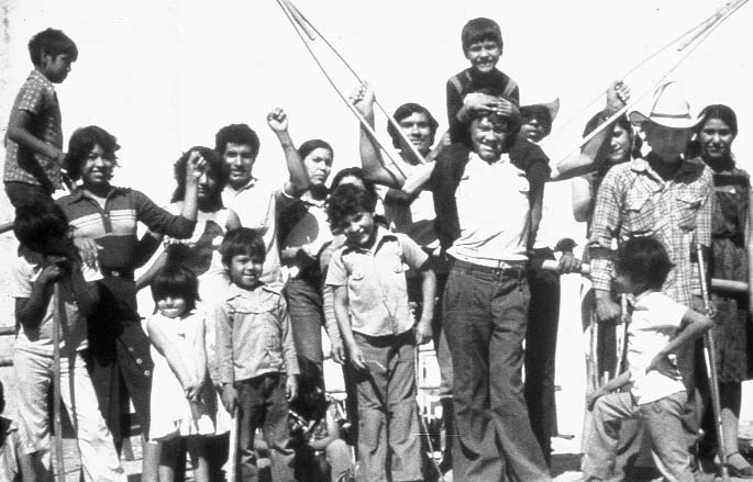 With a disabled child on his shoulders, Inez raises his crutches in a sign of victory. This scene is from a village theater skit to raise public awareness about the potential of disabled persons. It portrays Inez's own story: how he first came to PROJIMO as a boy for rehabilitation, and later became a skilled therapist helping others.