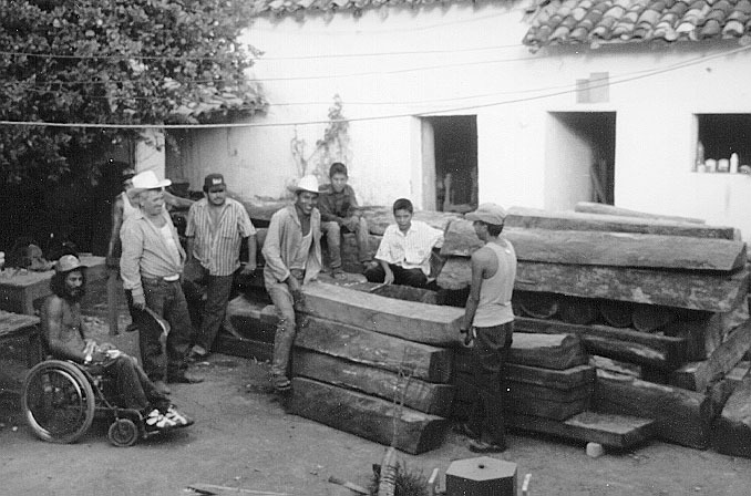 In the patio of the carpentry shop, villagers stack the beams they have dragged by mule from the riverbed.