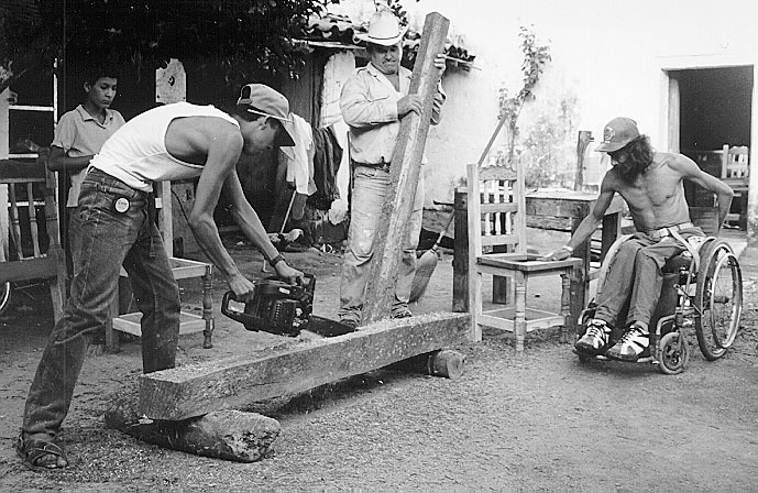 Martin skillfully cuts beams of Tepeguaje into planks, while Benigno helps and Mario works on a chair.