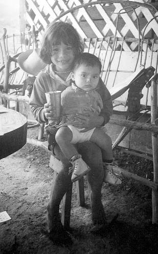 At Los Chavalitos children enjoy caring for one another. Here a girl who came here from a very troubled home situation, gives milk to a younger child. The older children take pride in helping to graze and milk the cows, and in producing much of their own food.