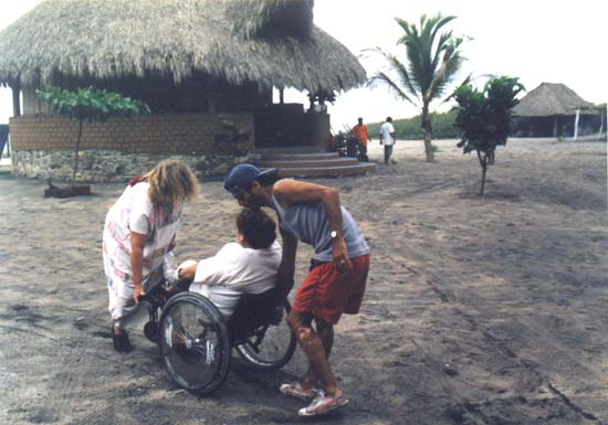 Anna Johansson, leader of Piña Palmera, helps Marta Heredia, grantee from Ashoka, roll her wheelchair through sand at an ecotourism project on the coast of Oaxaca.