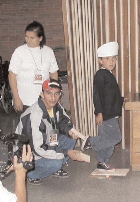 At a hands-on assitive technology workshop in Bogota, participants and a child with muscular dystrophy demonstrate the protective helmet and a heelcord stretching device, which they made together, using low-cost materials. (See page 6.)