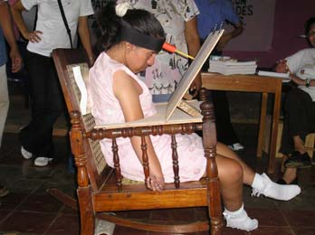 They made a pencil-holding pointer fixed to a head-band, for her to draw and write. But with the this rig she had to bend her neck down too much. It needed adjustments.