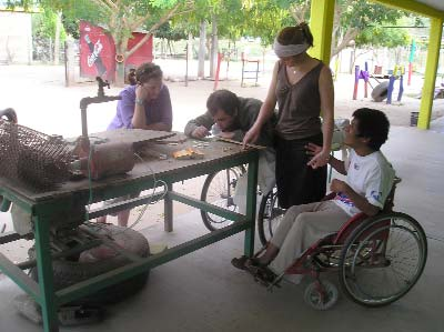 Alberto plays dominos with two occupational therapists, while Carlos, a boy with brain damage from a car accident, more or less looks on (he is largely blind). Alberto lies on a gurney so that his pressure sores will heal. The two therapists came to study Spanish and volunteer in the program.