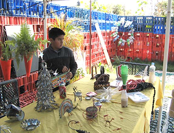 The museum display fills a yard walled in by colorful soft-drink crates. On this table are a variety of birds, animals, and bugs made from bits of wire, Popsicle sticks, and tin cans. 
