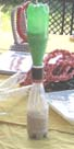 Two plastic juice bottles are joined and filled with sand to form an hourglass.