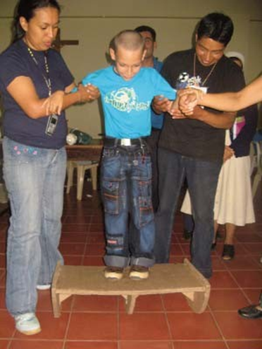 Walter David’s group also made him a balance board completely out of laminated cardboard, to help the boy to improve his balance and to stretch his tight heel cords by rocking back and forth on it.
