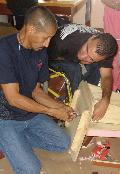 León Darío (seated on yellow wheelchair) assists in the construction of his own standing frame.