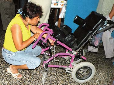 Estrella’s group attempts to adjust her wheelchair.