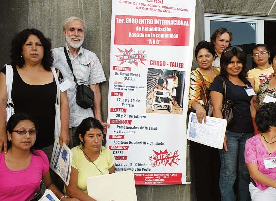 Some of the workshop participants stand with David Werner next to a placard announcing the pre-workshop seminar in Chimbote, which was held in the auditorium of the Municipal Hospital.