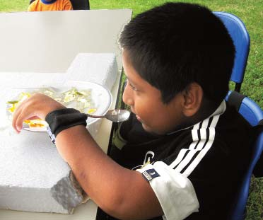 Daniel and his group also experimented with a wrist band holding a spoon, and an arm support for leverage, until he was able to lift the spoon to his mouth. Here he shows how he can now eat by himself with a spoon.