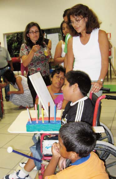 At the closing plenary Daniel proudly shows how he can take colored marking pens from a simple foam-plastic rack with his mouth, and draw using his new wheelchair tray and adjustable stand.