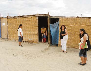 Alejandro and his mother stand in the doorway of his hut.