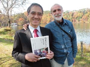 Visiting a local lake in Saki, Dr. Toru Honda (left), the founder of SHARE, holds a copy of the new Japanese translation of Where There Is No Doctor, by David Werner (right). 