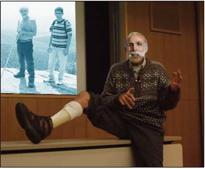 At a seminar at the Tokyo Children’s Rehabilitation Hospital, David Werner shows the plastic leg brace made for him by Marcelo, a disabled village rehab tech at PROJIMO, in Mexico. The braces worked better than costly ones made by US professionals, because Marcelo worked with David as an equal and partner in the problem-solving process. Behind him is a projected image of David at the top of a mountain he climbed.