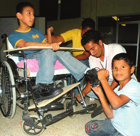 In a workshop David Werner facilitated in Guayaquil, Ecuador in 2009, participants and a young friend fit a footrest onto Jeferson’s wheelchair.