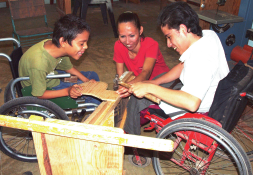 Moises (on right)—a youth with spina bifida at PROJIMO—helps build a standing frame for Jesus (on left), while Jesus and his mother assist. Moises has had a lot medical crises, and now his mother is in need of potentially life-saving surgery. See page 7.