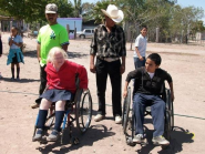 Non-disabled children participate in a wheelchair race over rough terrain.