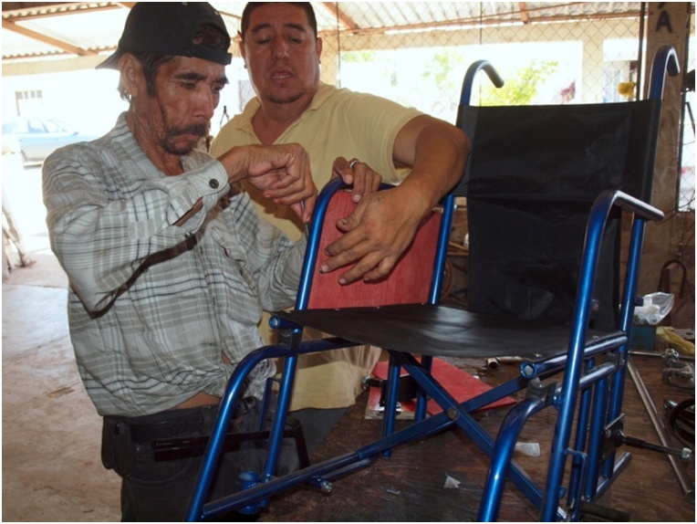 In the workshop, Yasmín's husband, Armando, teaches Miguel Angel's grandfather to help in the construction of wheelchairs.