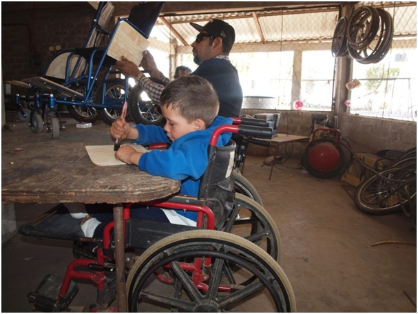 Here Miguel Angel helps Tomas varnish the side panel of a wheelchair they are building.