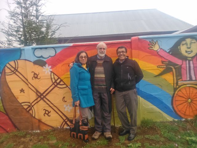 Eliana Mellado and Eduardo Herrera, director and co-directors of the School of Occupational Therapy, pose with me in front of the mural painted by members of the Union of Children and Parents for Normal Integration.