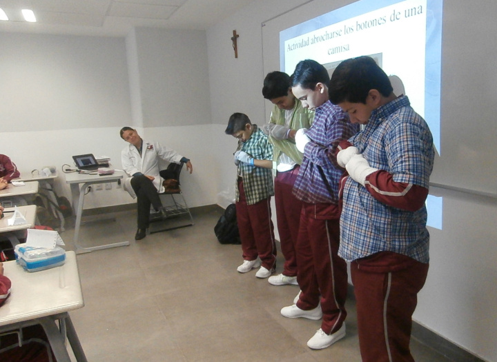 To learn how difficult some activtieis can be with the manual atrophy caused by CMT, Tomás’s classmates put stockings on their hands and try to button their shirts.